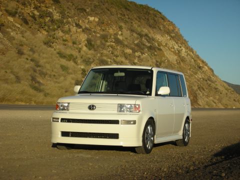 2006 Scion xB - White 2006 Scion xB parked on a dirt road with a hillside and blue sky in the background.