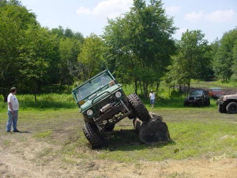 1992 Ford Bronco - Several off-road vehicles are gathered in a grassy area with trees in the background.