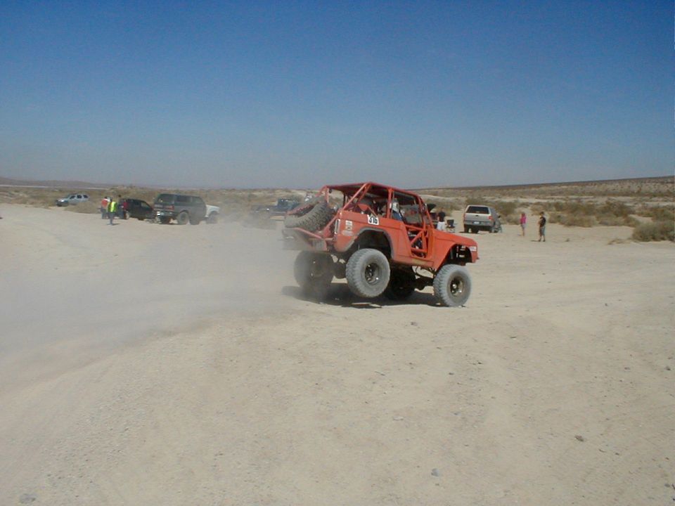 Orange 1996 Ford Bronco off-road vehicle airborne, rear spare tire visible