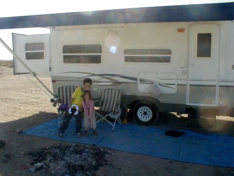 1996 Ford Bronco - Camping scene with two people relaxing beside a recreational vehicle.