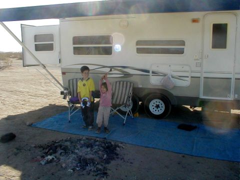 1996 Ford Bronco - Children enjoy the outdoors next to a parked camper trailer, with a fire pit nearby.