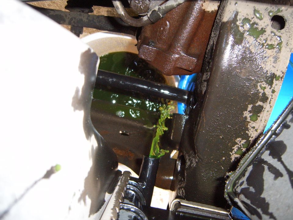 Close-up of a vehicle's coolant system with green fluid leaking from a hose connection
