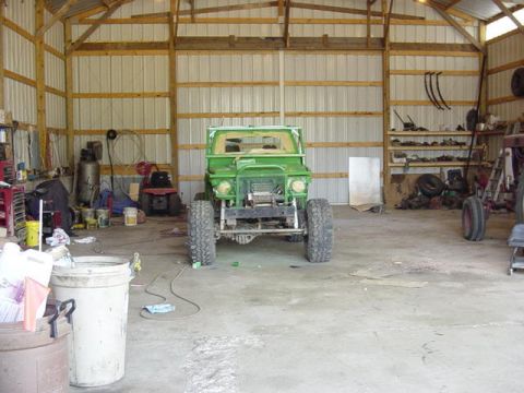 1992 Ford Bronco - A green vehicle is parked inside a metal-sided garage with tools and equipment visible in the background.