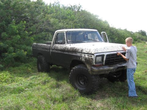 1974 Ford F-100 - A Ford pickup truck is parked in a field with a person standing beside it.