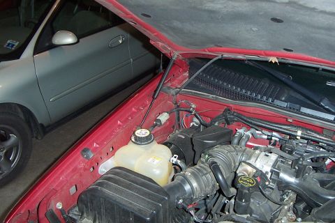 2005 Ford Explorer - The engine bay of a red Ford Explorer is visible, with a silver car parked alongside it.