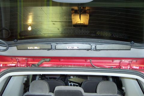 2005 Ford Explorer - Rear interior view of a red SUV, with seats visible and a reflection on the rear window.
