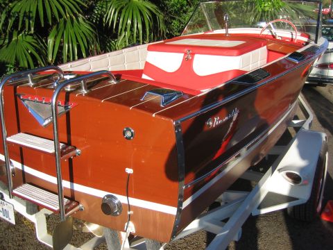 1996 Ford Bronco - A classic wooden boat with a red and white interior sits on a trailer, ready for the water.
