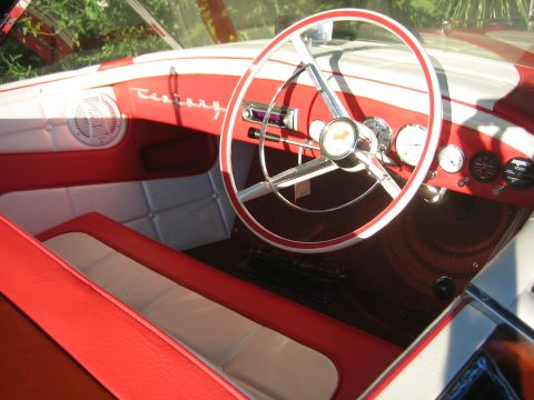 1996 Ford Bronco - The custom interior of a boat features red and white upholstery, a vintage steering wheel, and a dashboard with gauges.