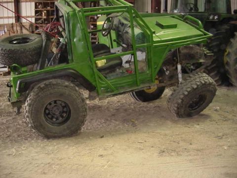 1992 Ford Bronco - A modified green off-road vehicle sits in a garage with a tractor in the background.