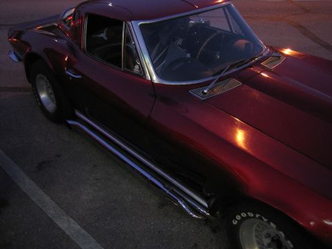 1996 Ford Bronco - A maroon coupe with side pipes and chrome trim is parked in a lot at dusk.