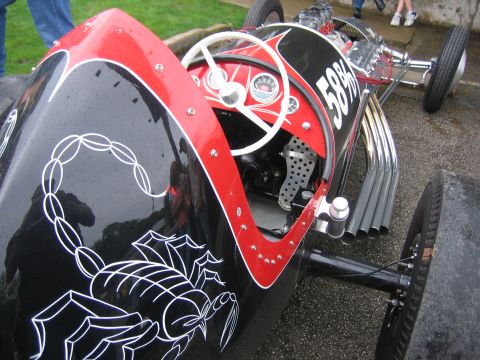 1996 Ford Bronco - Overhead rear-quarter view into the open cockpit of a black and red belly-tank/lakester-style race car, with a white pinstriped scorpion on…