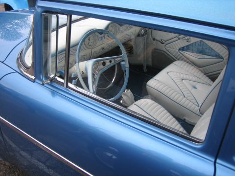 1996 Ford Bronco - The interior of a blue car features white seats with blue stitching and a custom steering wheel.