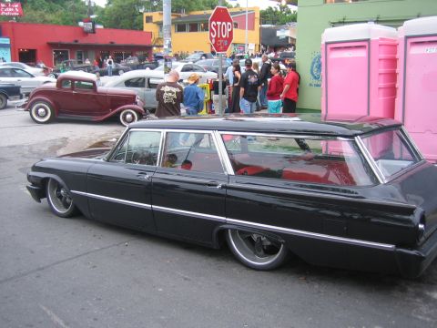 1996 Ford Bronco - A black station wagon with a bright red interior is parked on the street, its custom lowered suspension and large aftermarket wheels.