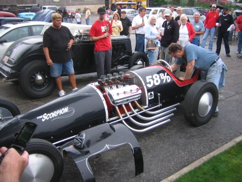 1996 Ford Bronco - A group of people gather around a custom race car with a prominent engine and racing numbers.