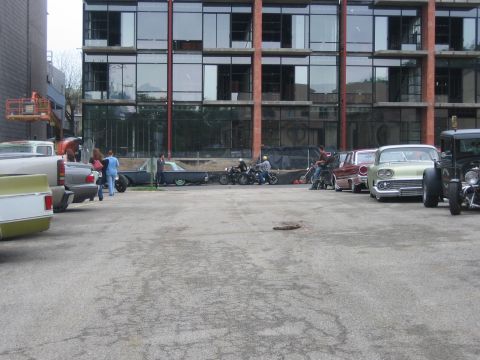 1996 Ford Bronco - A collection of classic vehicles, including cars and motorcycles, are parked outside a contemporary building.