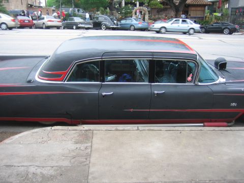 1996 Ford Bronco - A custom-built, long-wheelbase sedan with a matte gray finish and red accents is parked curbside.