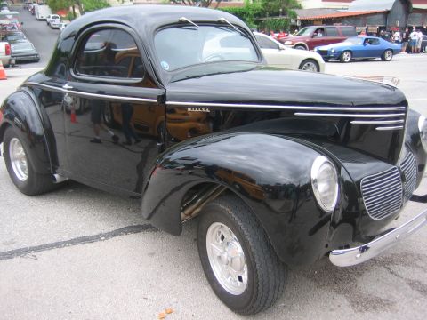 1996 Ford Bronco - A classic black Willys coupe is parked on a street with other vehicles in the background.