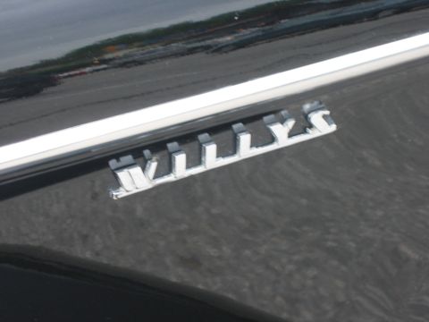 1996 Ford Bronco - A close-up view of a chrome emblem that reads "WILLYS" on a dark vehicle panel.
