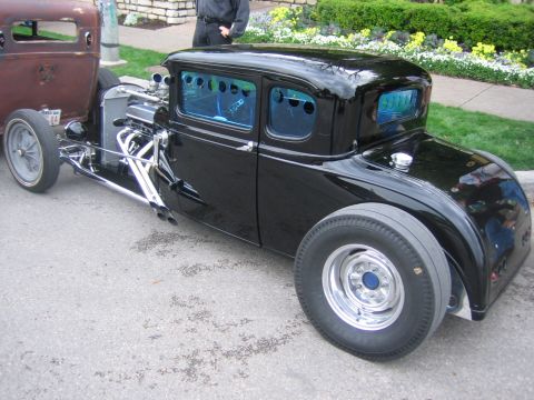1996 Ford Bronco - A black hot rod coupe with a prominent exposed engine and distinctive blue-tinted windows is parked next to another vehicle.