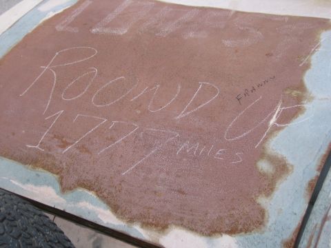 1996 Ford Bronco - Chalked messages on a weathered vehicle hood indicate 'Round Up 1777 Miles' and a name.
