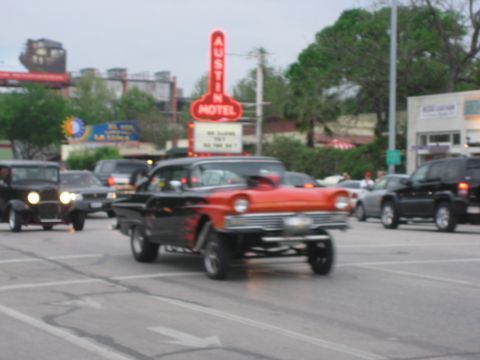 1996 Ford Bronco - A custom two-tone hot rod with flame decals and a lifted front end cruises past the iconic Austin Motel sign.