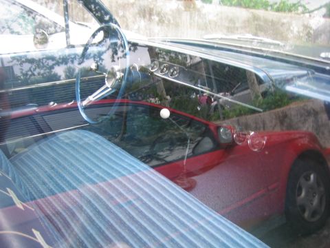 1996 Ford Bronco - Interior view of a red car blue striped seats and a classic blue steering wheel with a white shift knob.