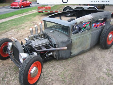 1996 Ford Bronco - Custom hot rod with a prominent V8 engine and exposed exhaust pipes sits on a dirt lot.