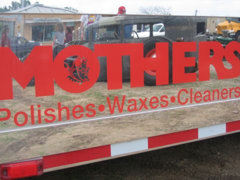 1996 Ford Bronco - A vintage car is reflected in the side of a trailer with 'MOTHERS Polishes Waxes Cleaners' lettering.