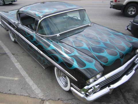 1996 Ford Bronco - A classic black car with teal flame paintwork is parked on a street.