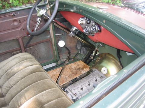 1996 Ford Bronco - The interior of a vintage vehicle shows a manual transmission, a red dashboard with gauges, and a weathered floor.