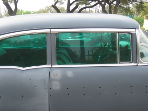 1996 Ford Bronco - A vintage car with distinctive green tinted windows and numerous small holes on its side panel.
