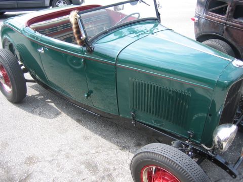 1996 Ford Bronco - A vintage green roadster is parked next to another classic car.