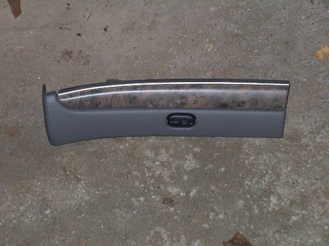 2000 Ford Crown Victoria - Interior trim panel with wood grain and a button, likely from a car.