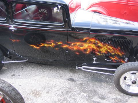 1996 Ford Bronco - A black hot rod with custom flame graphics is parked next to a red vehicle.
