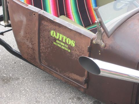 1996 Ford Bronco - A close-up view of a weathered hot rod's side panel, adorned with custom lettering and a shiny exhaust pipe.