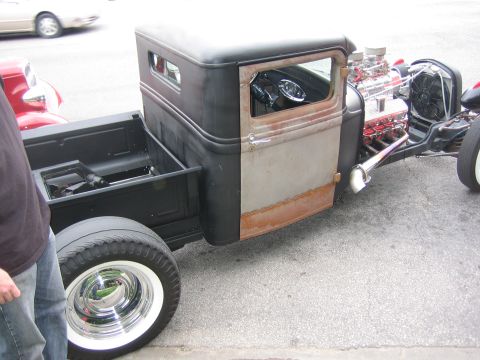 1996 Ford Bronco - A modified pickup truck with a large engine and custom wheels is parked on a street.