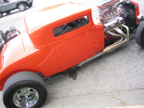 1996 Ford Bronco - A bright orange hot rod with a powerful engine and custom exhaust pipes sits on asphalt.