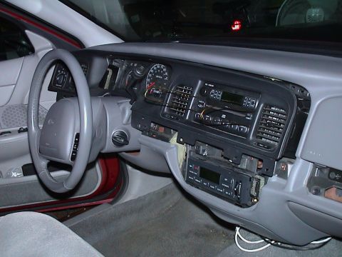 2000 Ford Crown Victoria - Grey interior of a red Ford sedan shot from the passenger side with the dash partially disassembled: the center bezel is pulled and the fac…