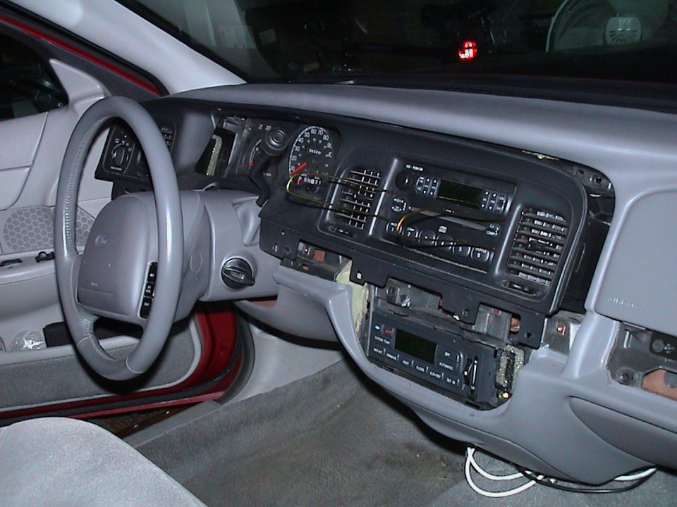 Grey Ford sedan dash with center bezel removed and radio and climate controls pulled loose
