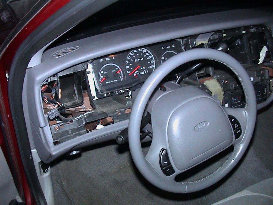 Red Ford sedan dash stripped to bare metal and wiring around the gauge cluster and grey steering wheel