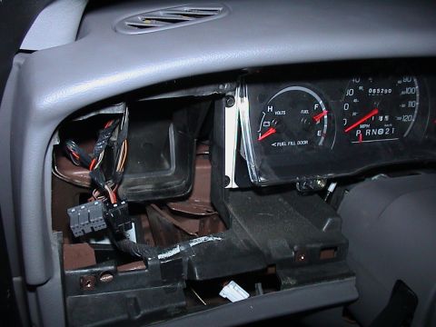 2000 Ford Crown Victoria - Close-up inside a gray Ford sedan dash with the instrument cluster pulled loose and tilted out of its opening, showing the volts and fuel g…