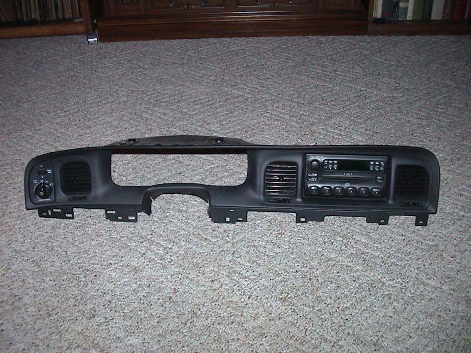 Removed Ford dash bezel with headlight switch, vents and factory CD radio on carpet