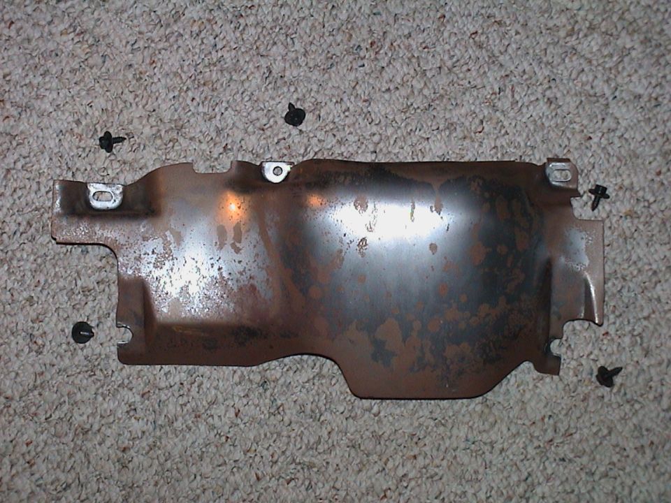 Rusty stamped-steel under-dash knee bolster bracket on carpet with black trim clips