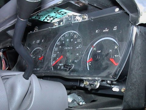 2000 Ford Crown Victoria - A dusty Ford instrument cluster sitting loose in the open dash opening, tipped toward the camera so the 120 mph speedometer, 65,291-mile od…