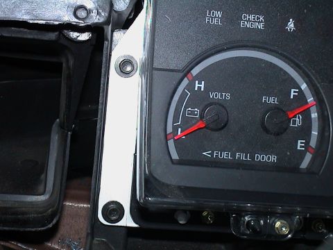 2000 Ford Crown Victoria - Extreme close-up of the left side of a Ford gauge cluster set into the open dash, showing the voltmeter and fuel gauge with a 'FUEL FILL DO…