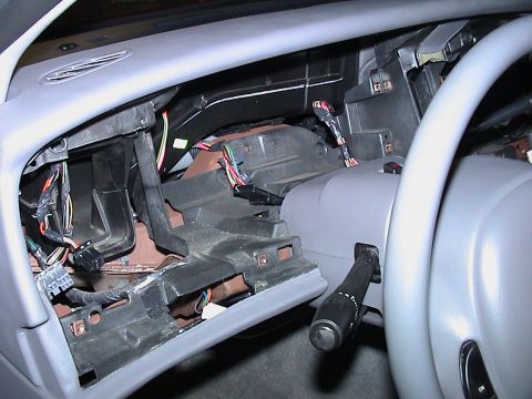 2000 Ford Crown Victoria - Driver-side dash of a grey-interior car opened up with the instrument bezel and cluster removed, revealing the black HVAC ducting, bare met…