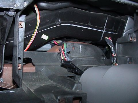2000 Ford Crown Victoria - Close-up behind a stripped dashboard showing the black plastic HVAC plenum and heater box, a flexible convoluted duct and the bare metal co…