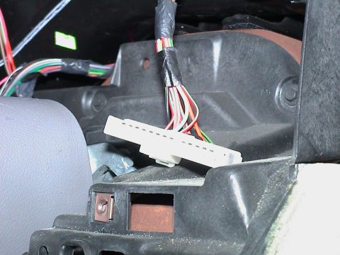 2000 Ford Crown Victoria - Close-up inside an opened dashboard showing a white flat multi-pin connector, the type that plugs into an instrument cluster, dangling on i…