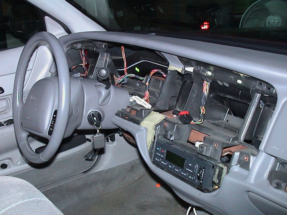 Grey sedan interior with the dashboard torn down exposing ducting, wiring and bare metal