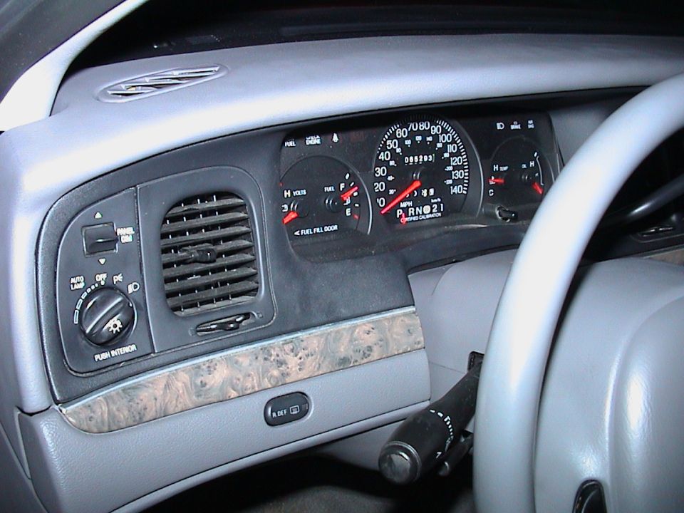 Grey Ford sedan dashboard with 140 mph certified-calibration cluster and woodgrain trim